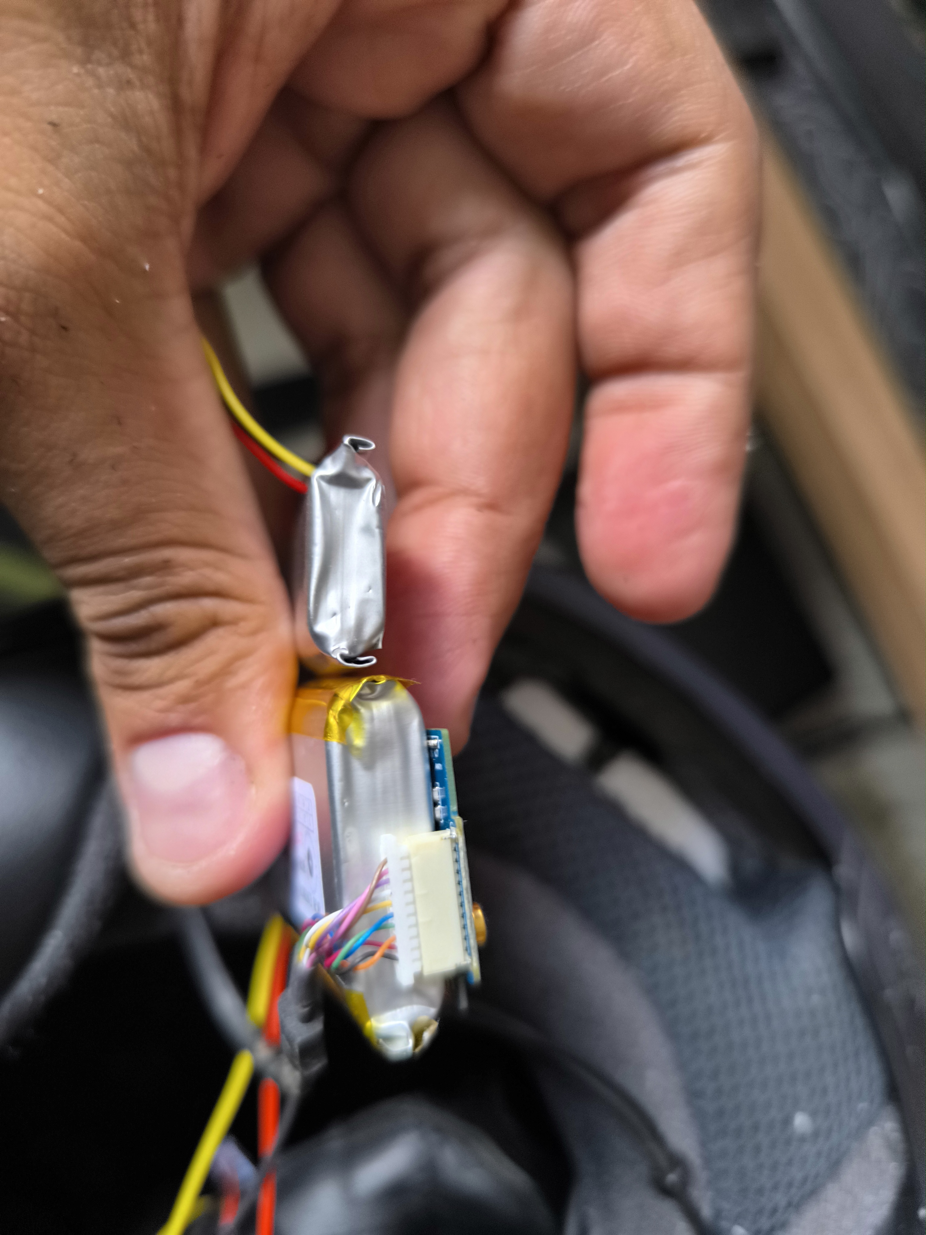 The two pouch batteries viewed from their edges, showing their different profiles beside the circuit board.