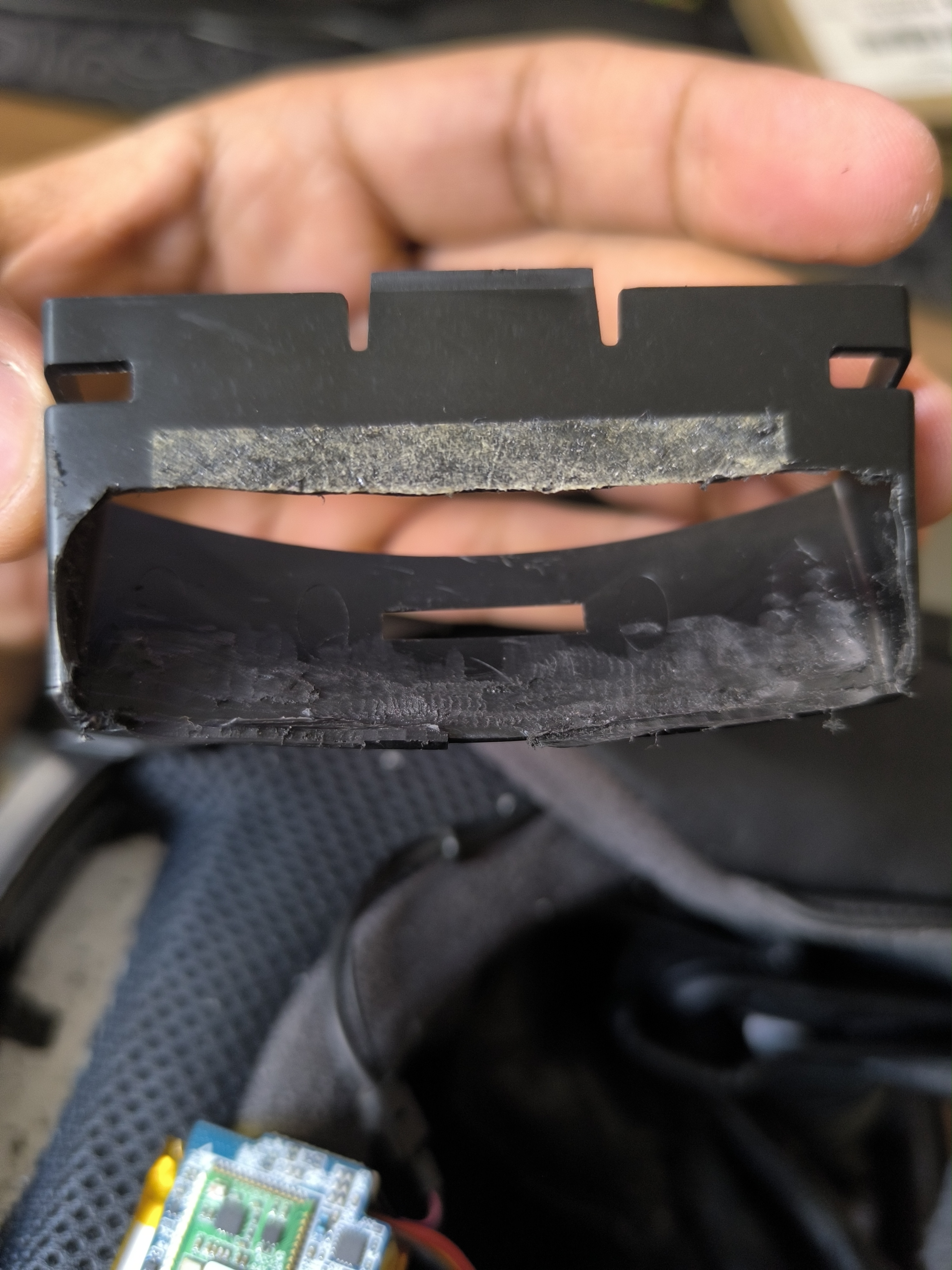 The removed black plastic mounting bracket, with material trimmed from its lower opening.