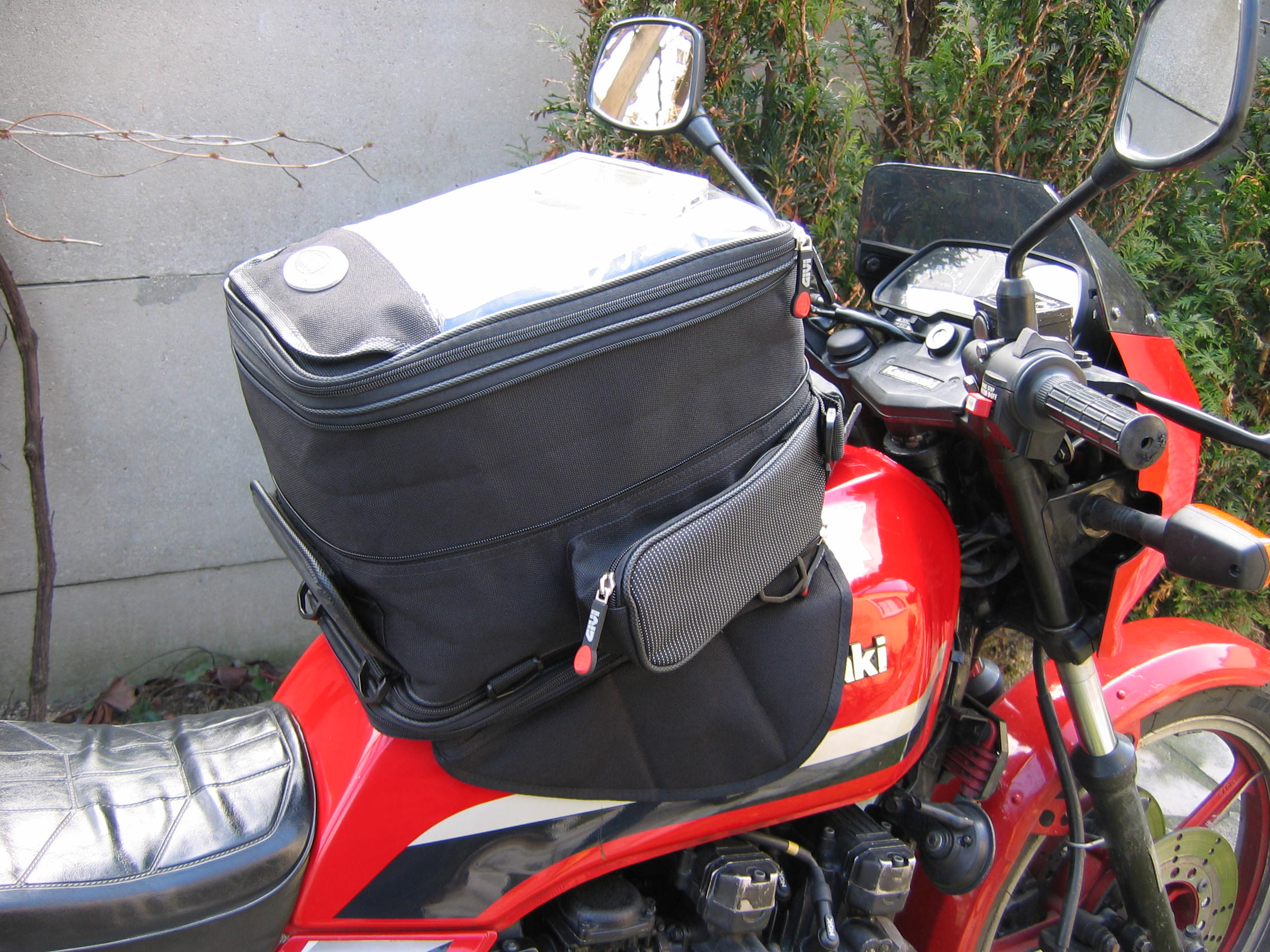 A GIVI-branded tank bag on a red motorcycle, showing the space occupied by tank-mounted luggage.